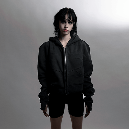 Woman wearing a black organic cotton fleece hoodie with sewn-in shoulder pieces and thumb holes, part of the SILHOUETTE collection.